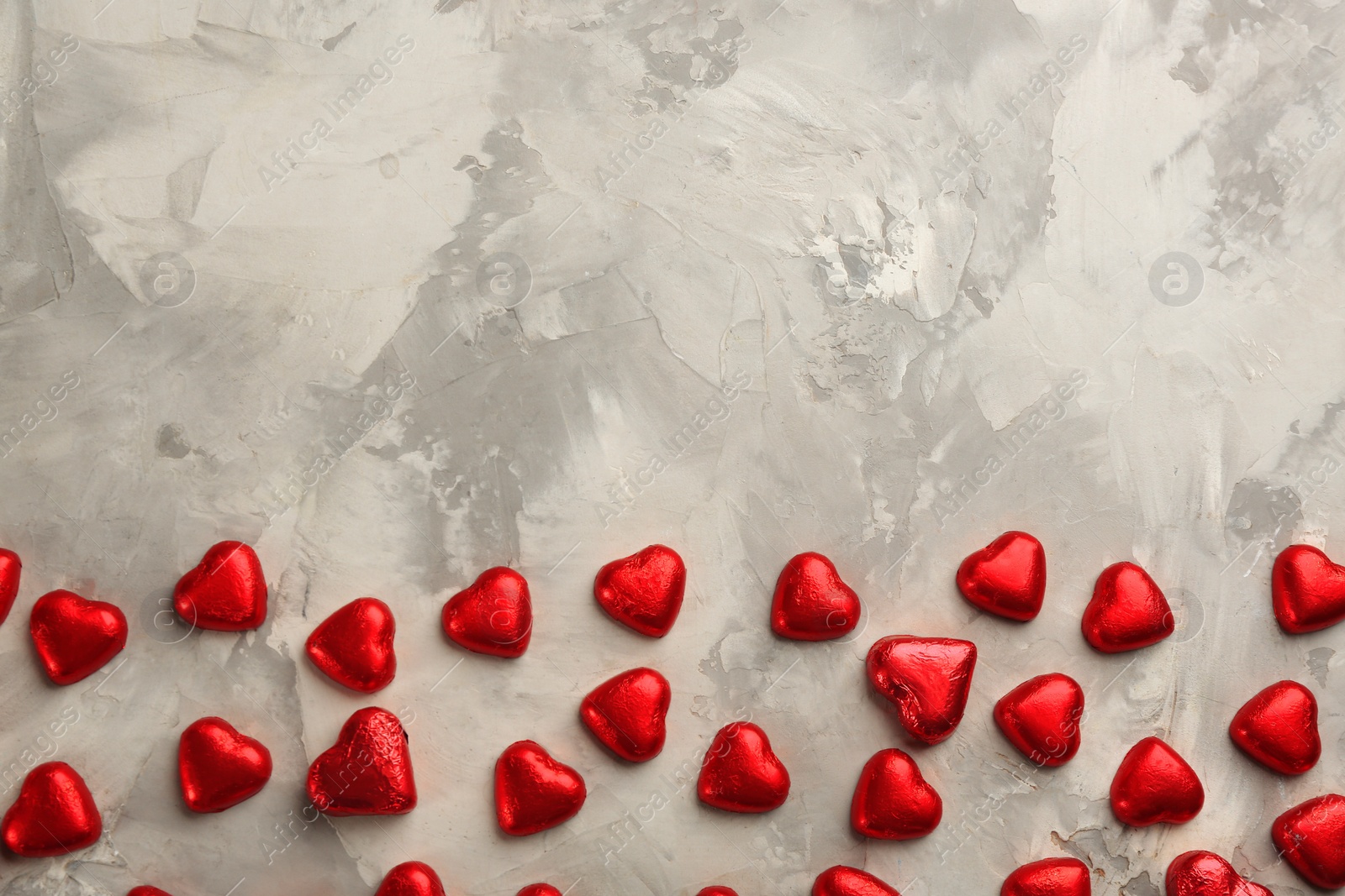 Photo of Heart shaped chocolate candies on light grey table, flat lay. Space for text