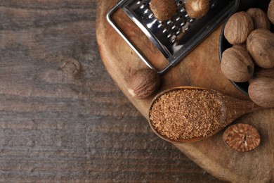 Photo of Spoon with grated nutmeg, seeds and grater on wooden table, top view. Space for text