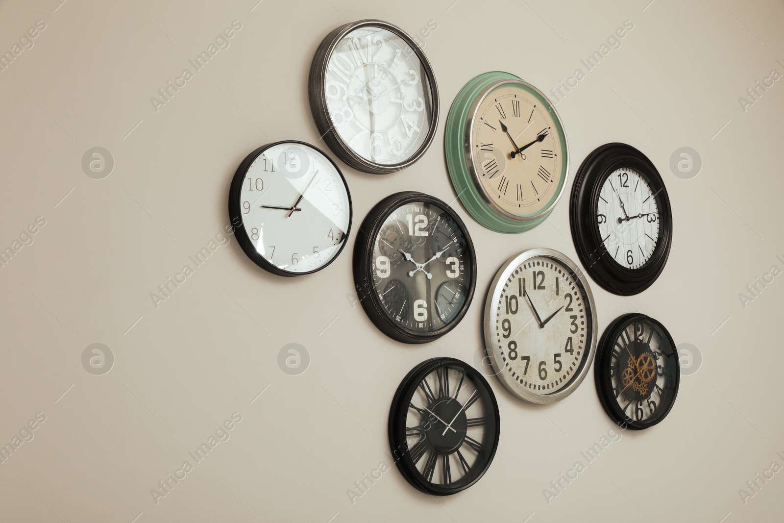 Photo of Many different clocks hanging on white wall.