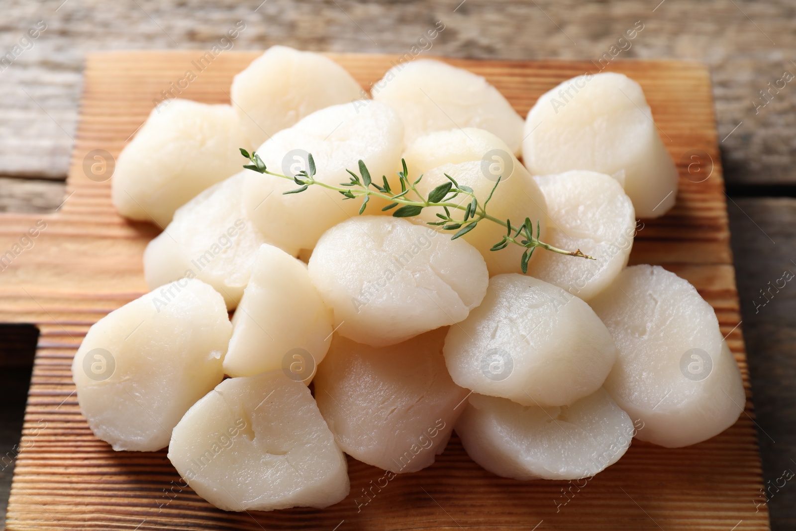 Photo of Fresh raw scallops and thyme on wooden table, closeup