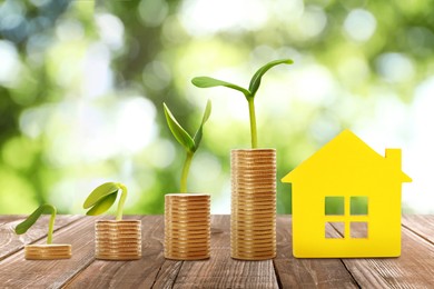 Real estate investing. House model and coins on wooden table