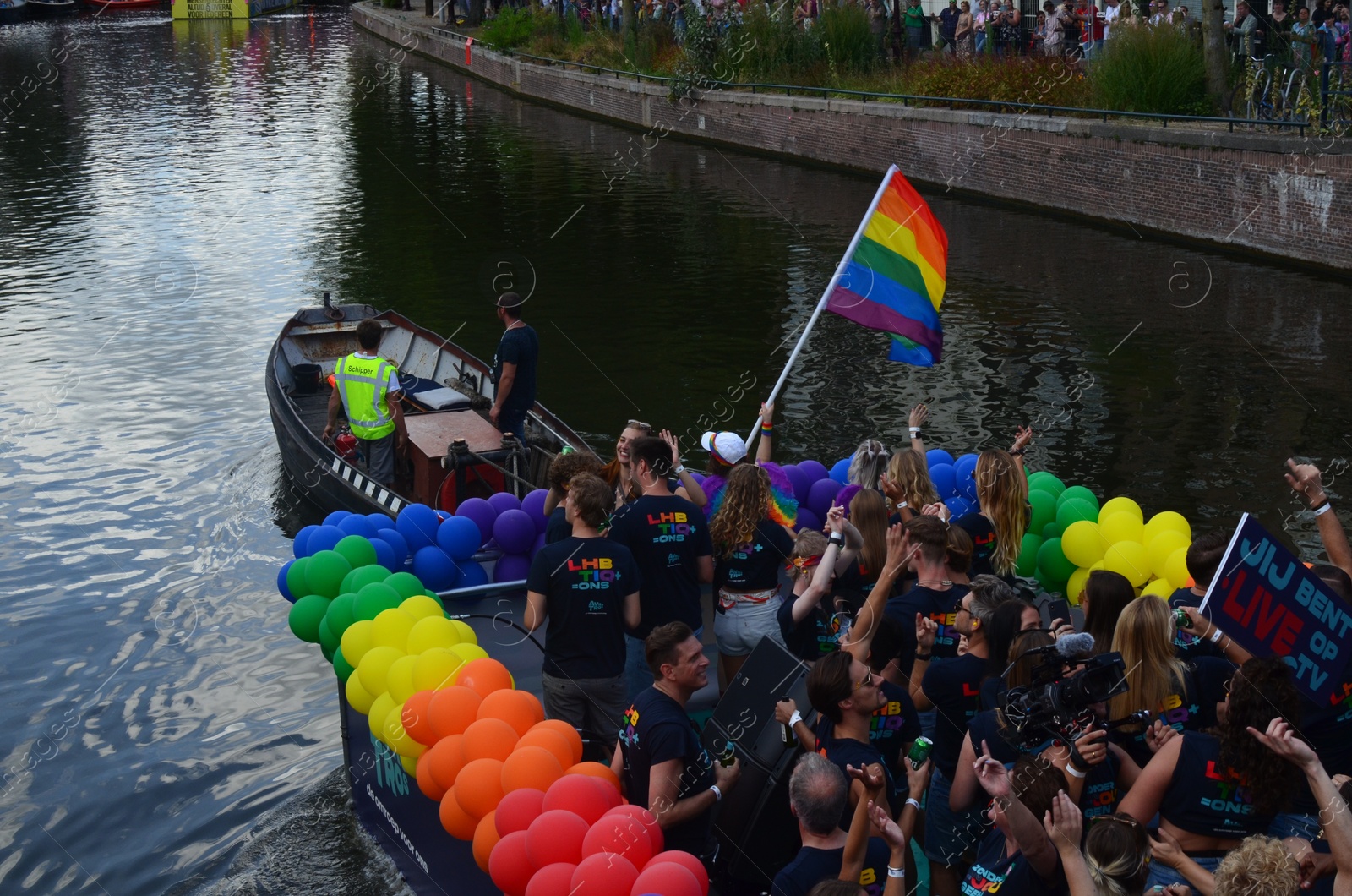 Photo of AMSTERDAM, NETHERLANDS - AUGUST 06, 2022: Many people in boats at LGBT pride parade on river