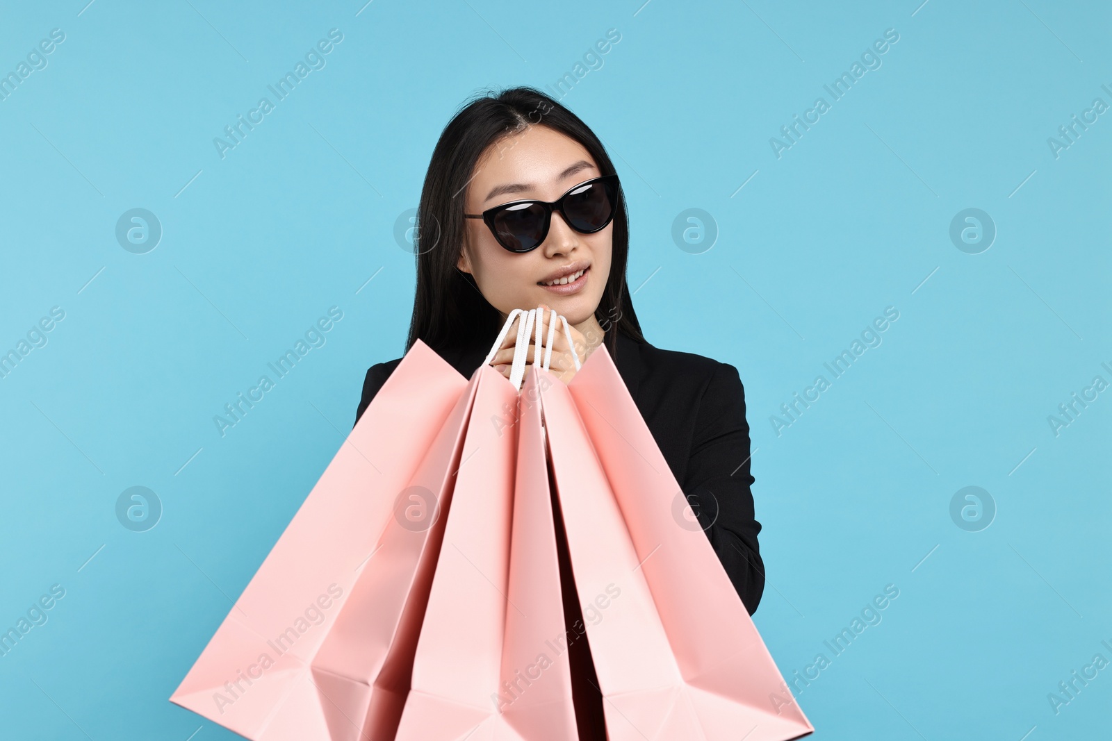 Photo of Smiling woman with shopping bags on light blue background