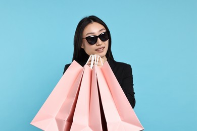 Smiling woman with shopping bags on light blue background