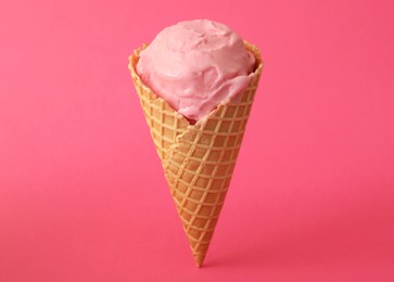 Photo of Delicious ice cream in waffle cone on pink background