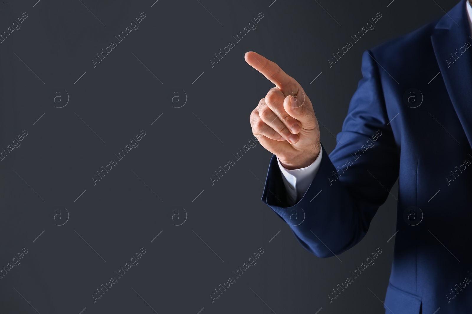 Photo of Businessman touching empty virtual screen against dark background, focus on hand