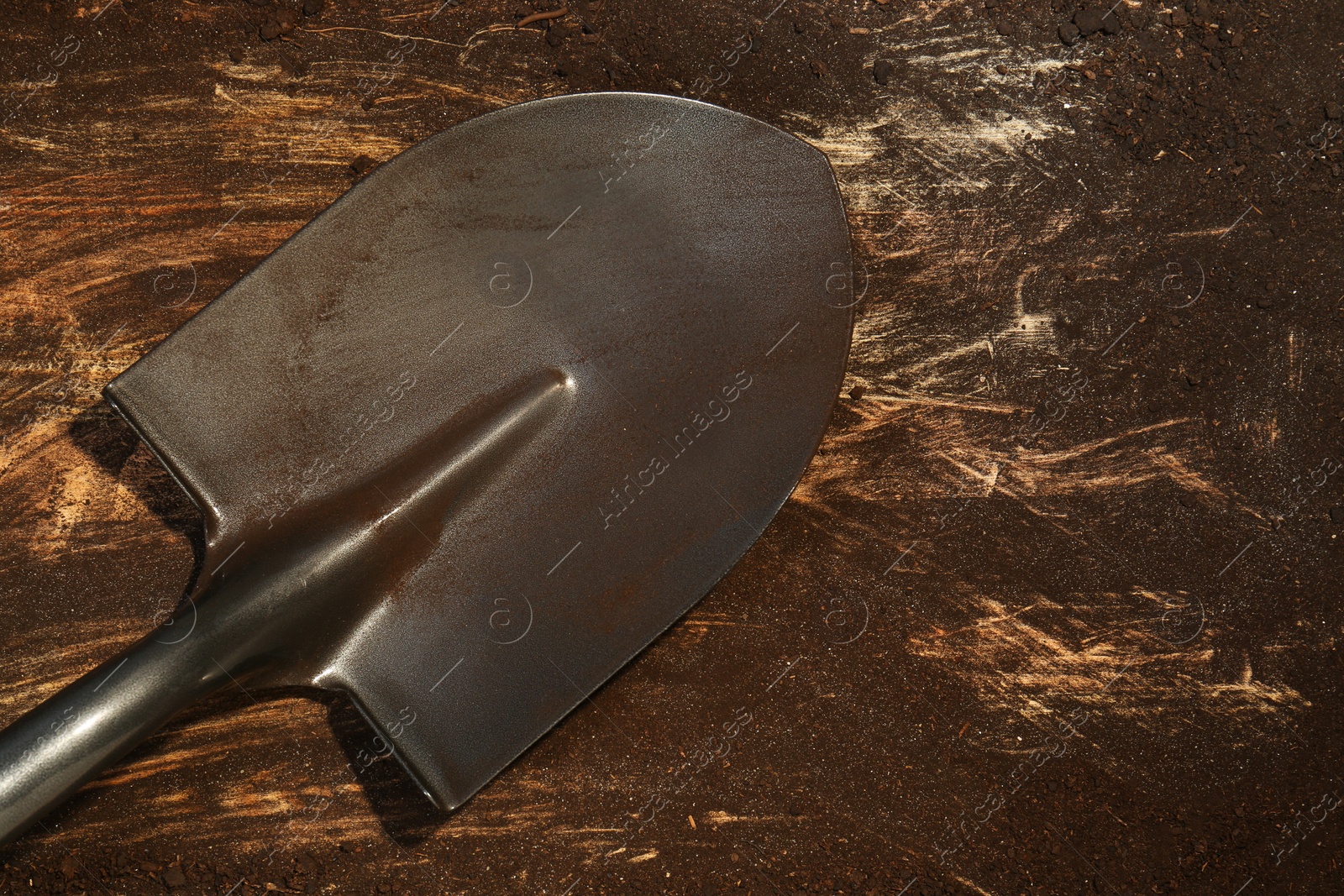 Metal shovel with fertile soil on dirty wooden surface, top view. Space for text Photo of Metal shovel with fertile soil on dirty wooden surface, top view. Space for text