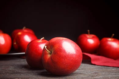 Photo of Ripe juicy red apples on black wooden table