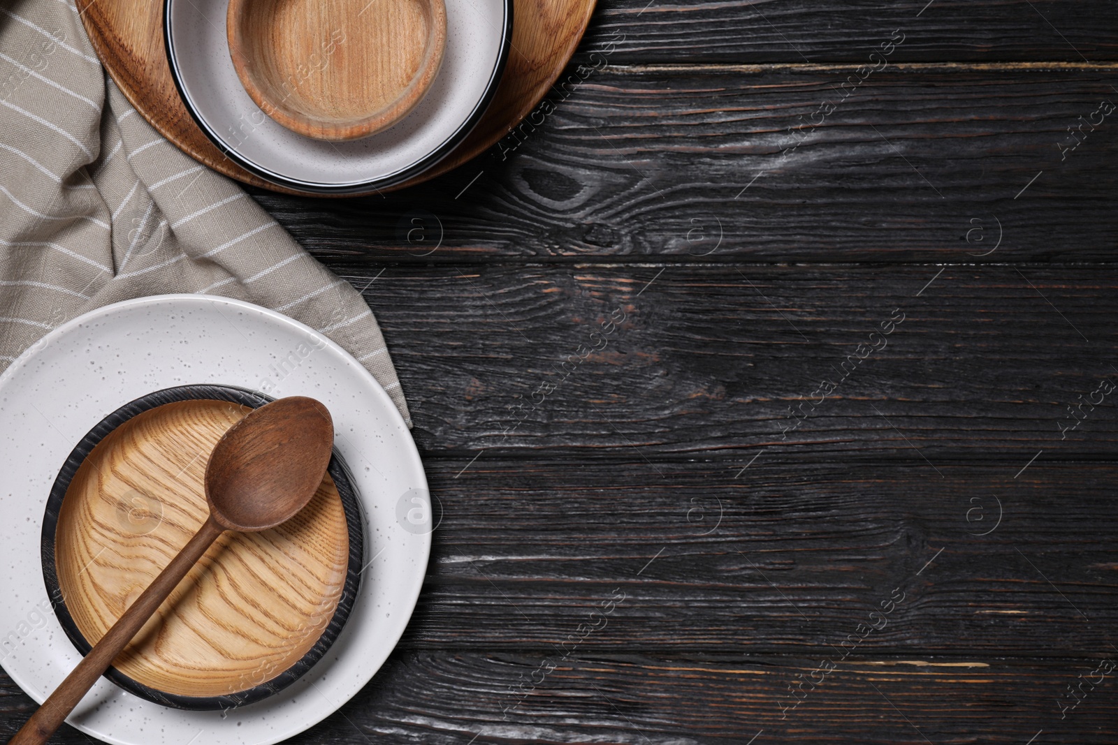 Photo of Flat lay composition with wooden dishware on black table. Space for text