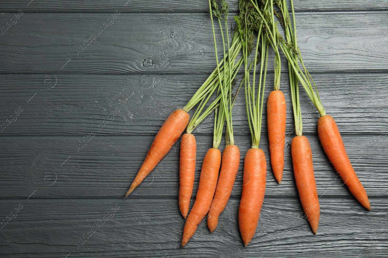 Photo of Ripe carrots on wooden background, top view