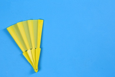 Photo of Yellow hand fan on light blue background, top view. Space for text