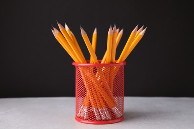 Many sharp pencils in holder on light table against black background