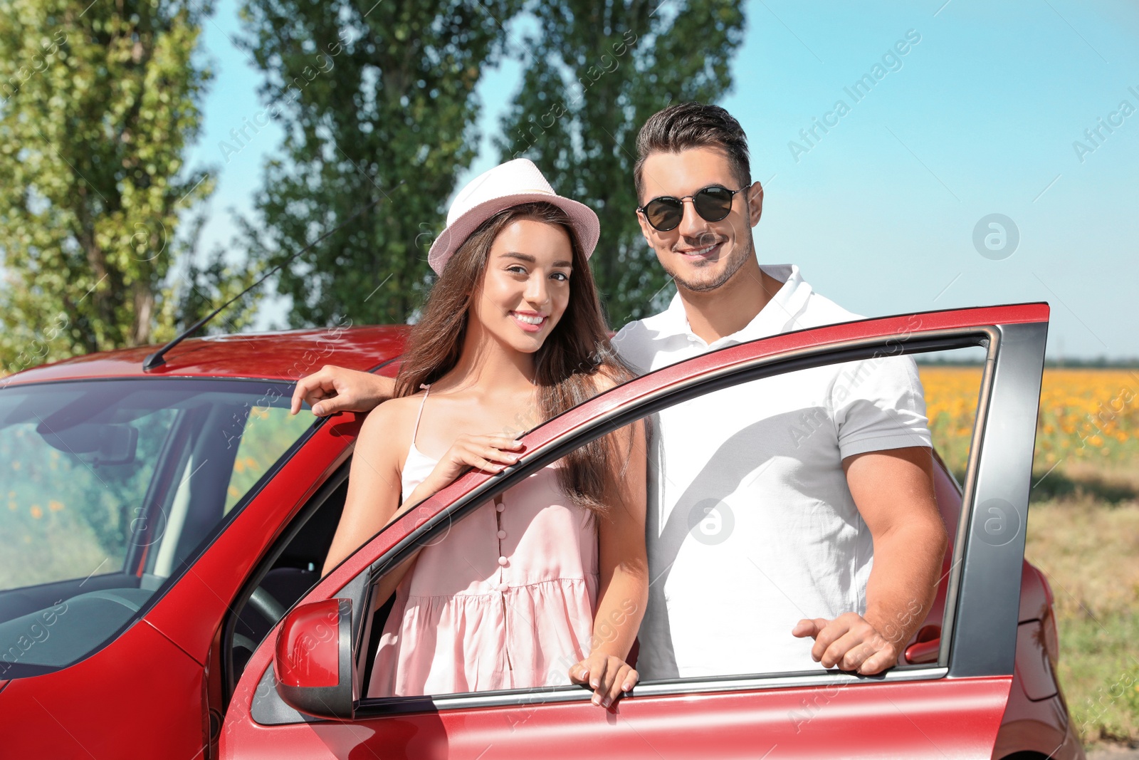 Photo of Happy young couple standing near car on road