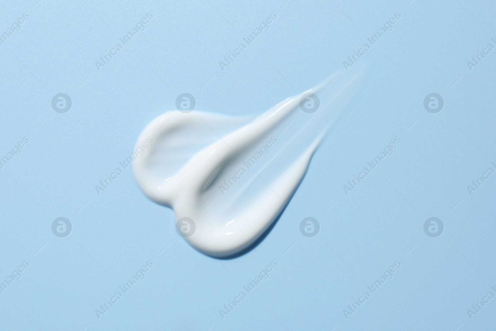 Photo of Sample of face cream on light blue background, top view