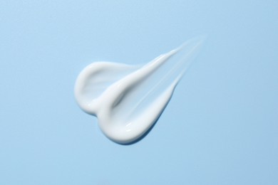 Sample of face cream on light blue background, top view