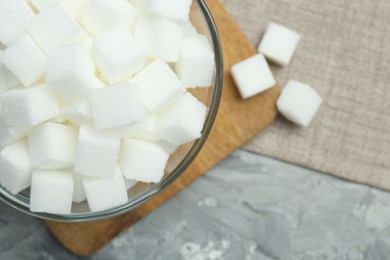 Photo of White sugar cubes in glass bowl on grey table, top view. Space for text