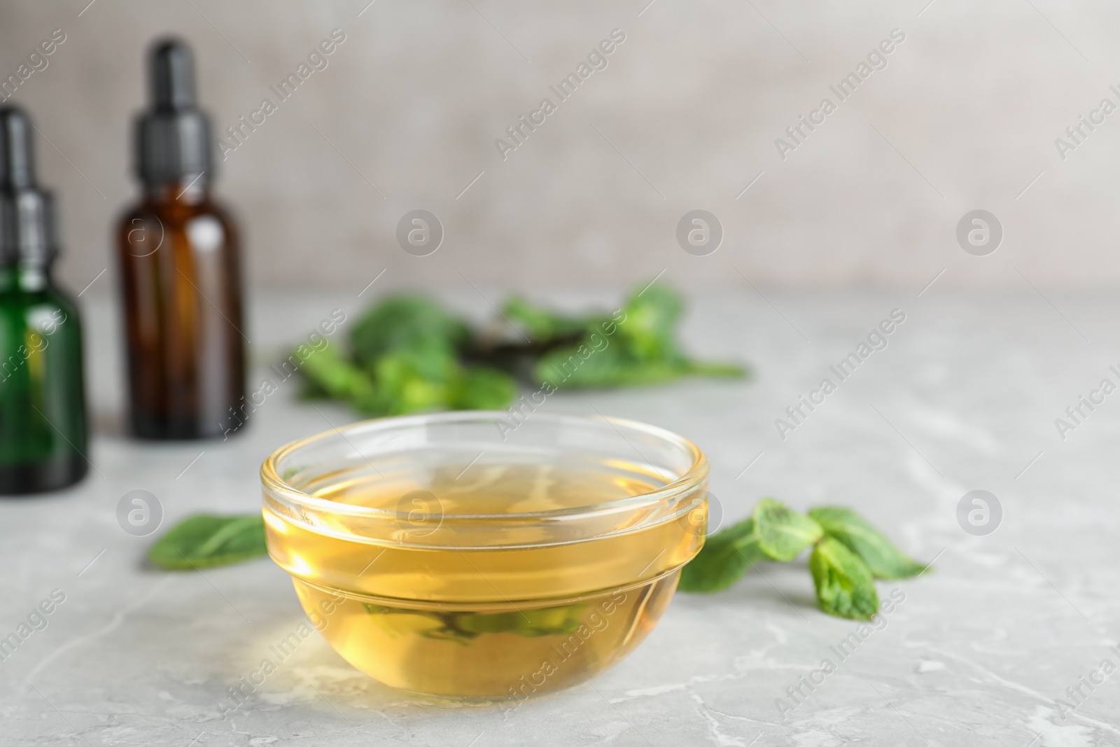 Photo of Bowl of essential oil on table. Space for text