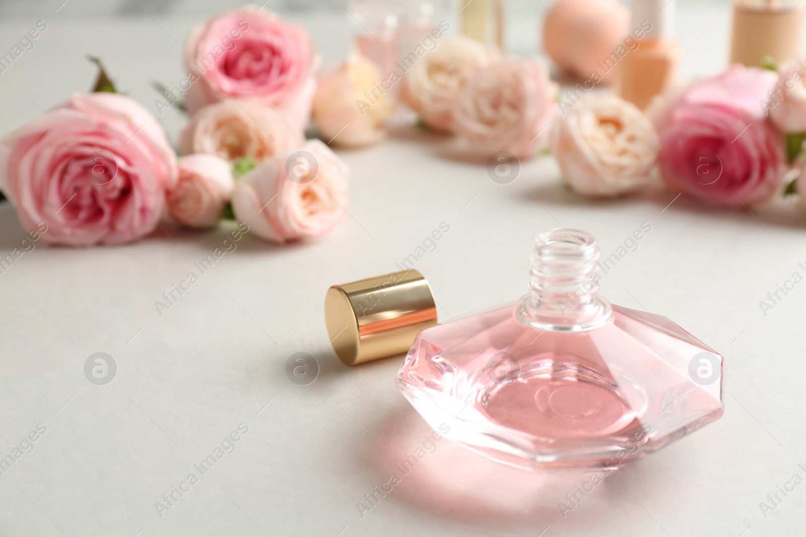 Photo of Bottle of perfume and roses on light background. Space for text
