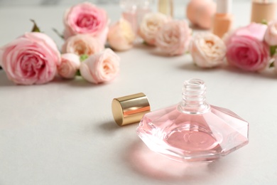 Bottle of perfume and roses on light background. Space for text