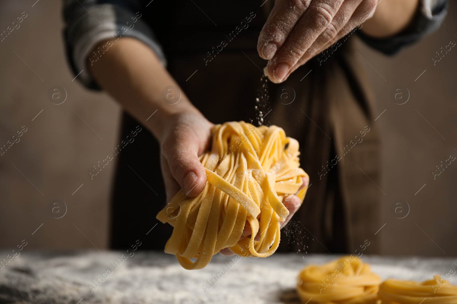 Photo of Woman holding pasta on brown background, closeup