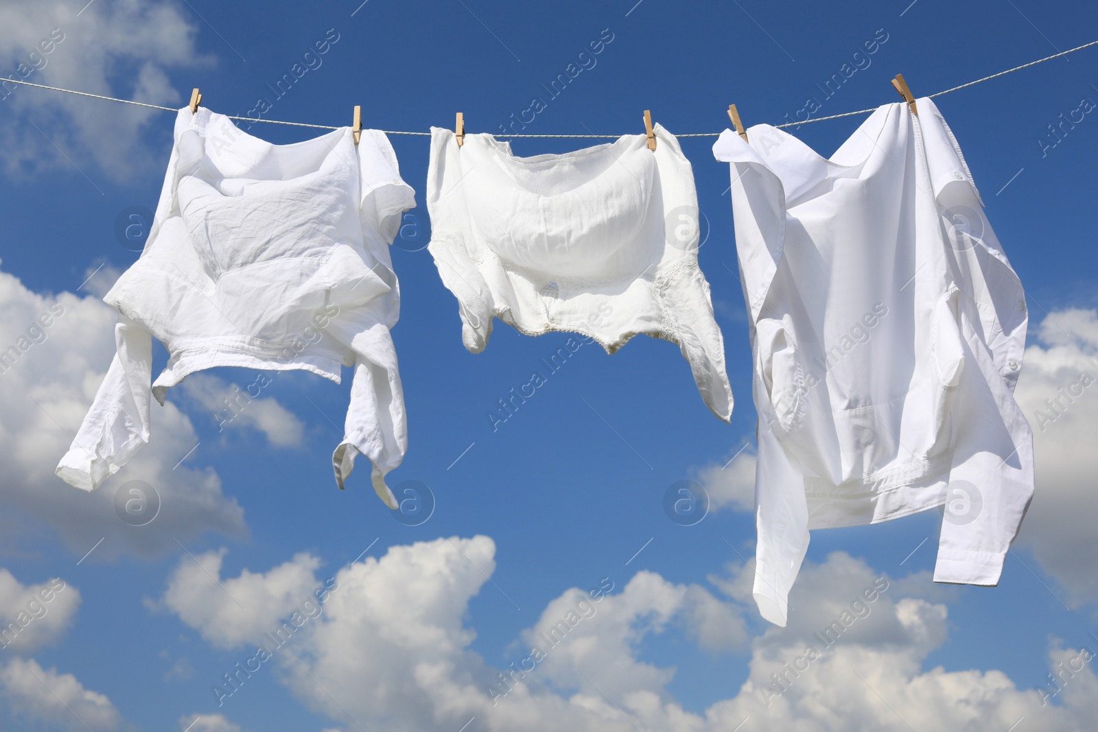 Photo of Clean clothes hanging on washing line against sky. Drying laundry