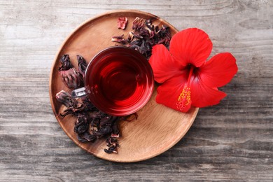 Delicious hibiscus tea and flowers on wooden table, top view