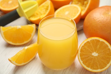 Photo of Freshly made juice, oranges and reamer on wooden table, closeup