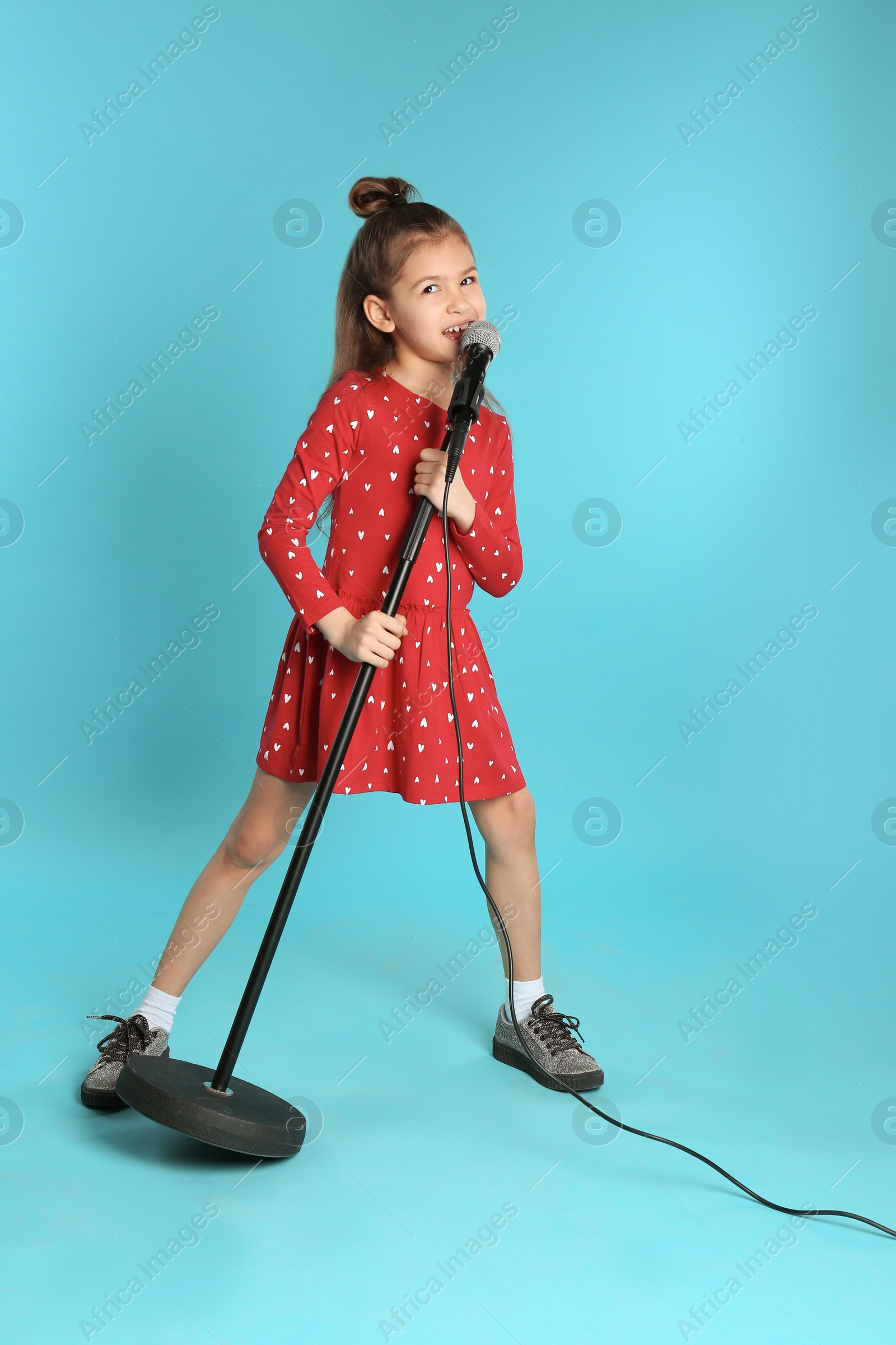 Photo of Cute funny girl with microphone on color background