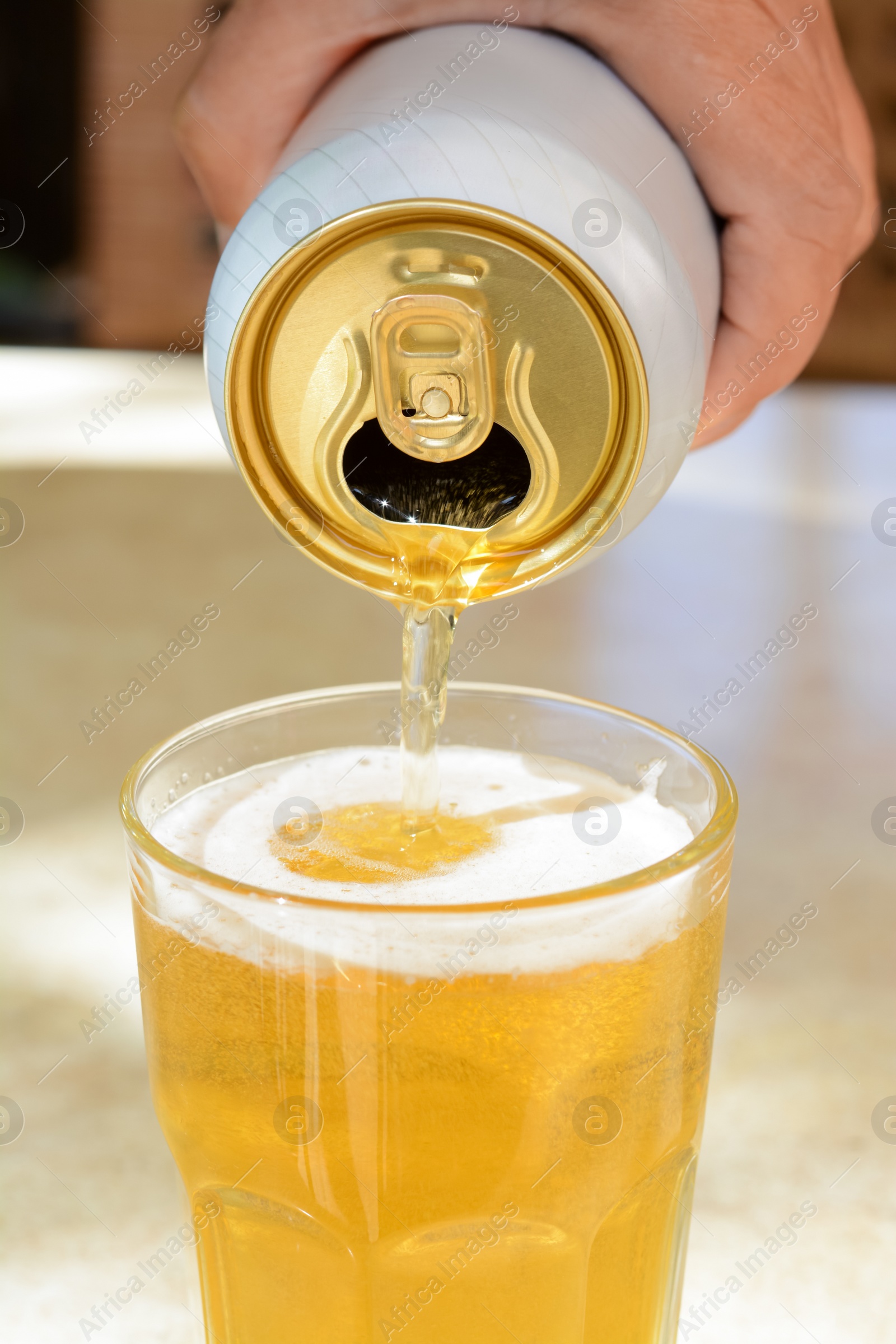 Photo of Man pouring beer from can into glass at table, closeup