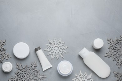 Photo of Flat lay composition with cosmetic products and snowflakes on light grey table, space for text. Winter skin care