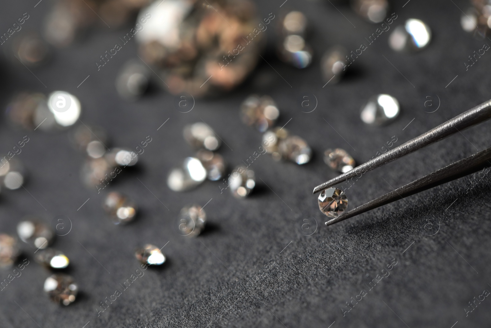 Photo of Tweezers with beautiful gemstone over grey table