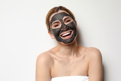 Photo of Beautiful woman with black mask on face against light background