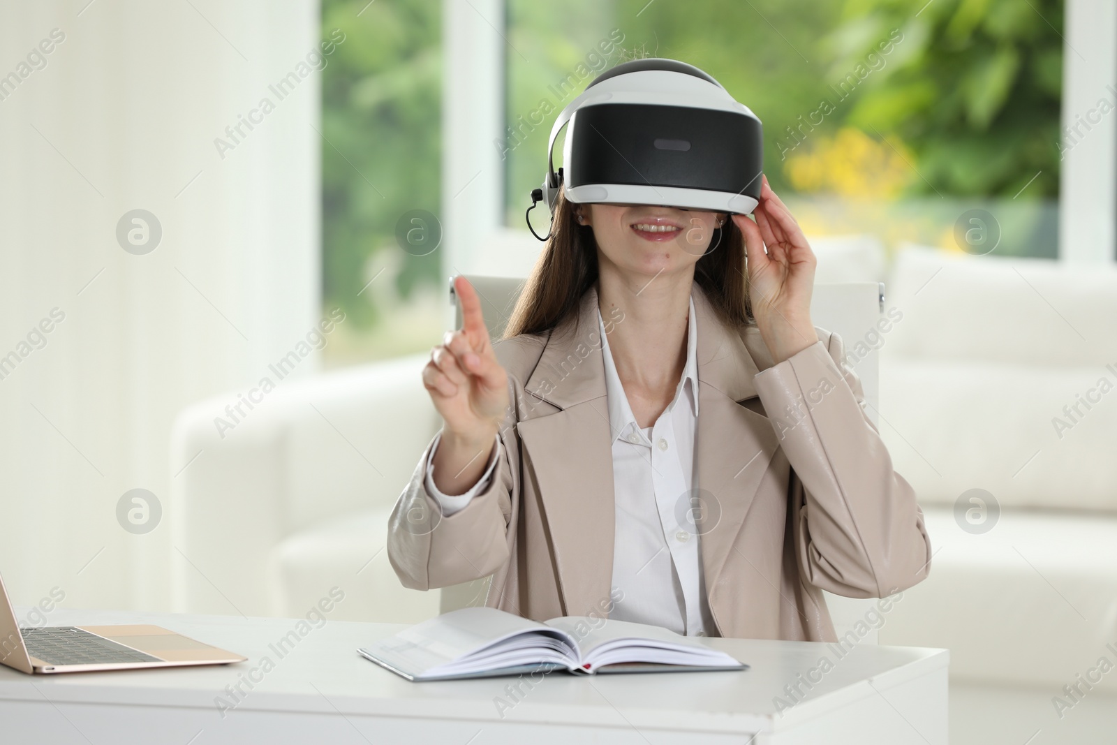 Photo of Smiling woman using virtual reality headset in office, space for text