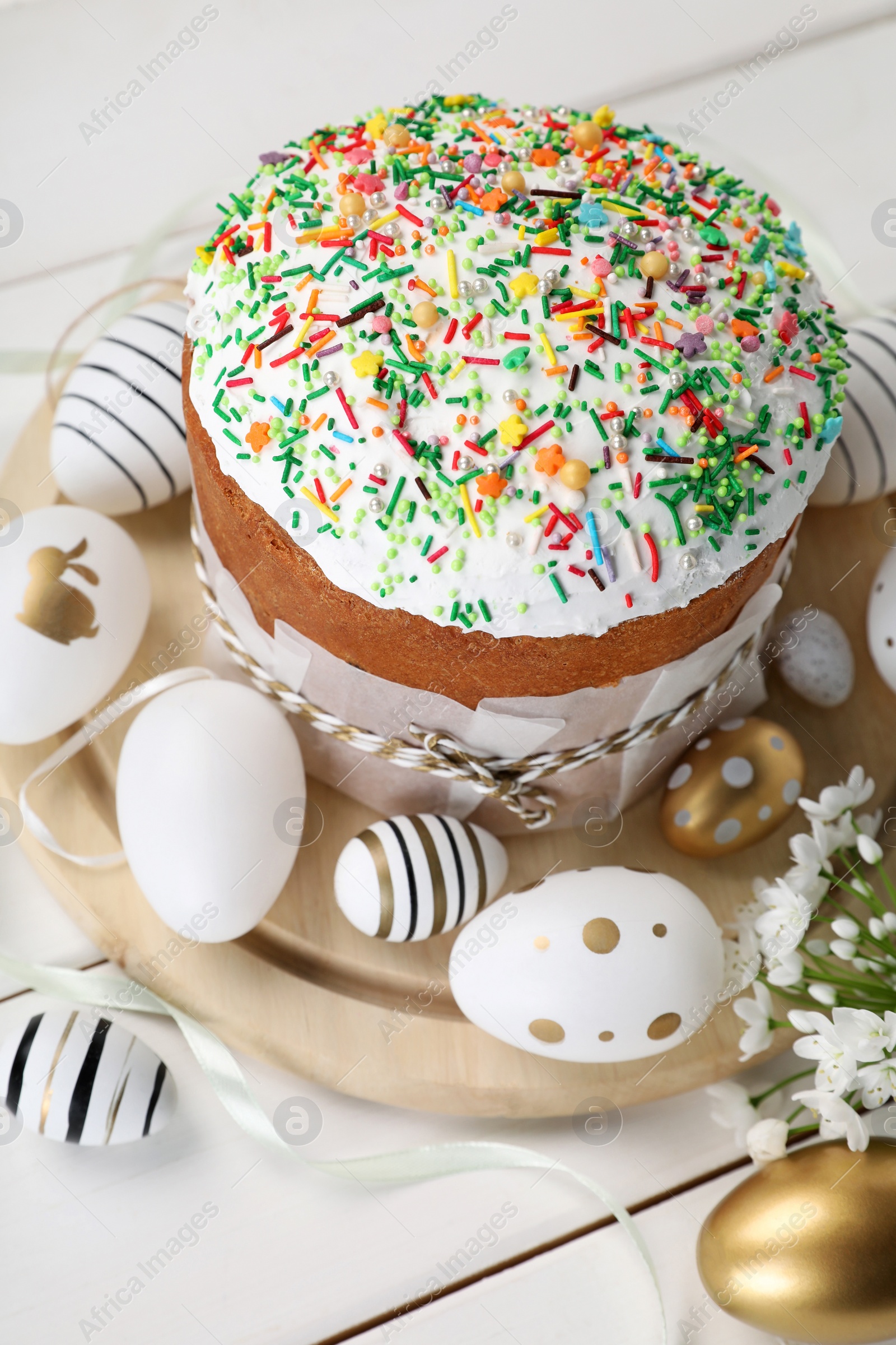 Photo of Traditional Easter cake with sprinkles and painted eggs on white wooden table