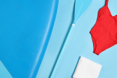 Flat lay composition with SUP board on light blue background. Water sport