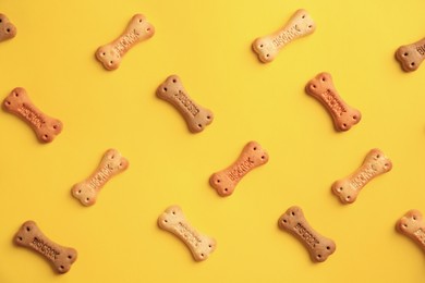 Photo of Bone shaped dog cookies on yellow background, flat lay