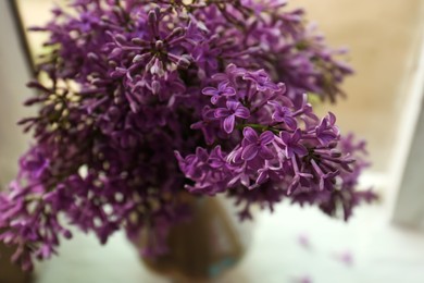Beautiful lilac flowers in vase on window sill indoors, closeup