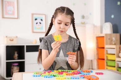 Little autistic girl playing with puzzles at home