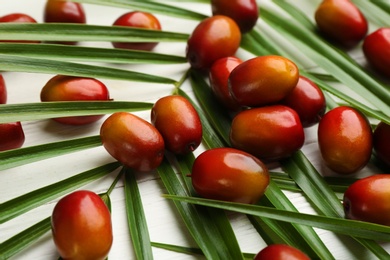 Photo of Palm oil fruits on white wooden table, closeup