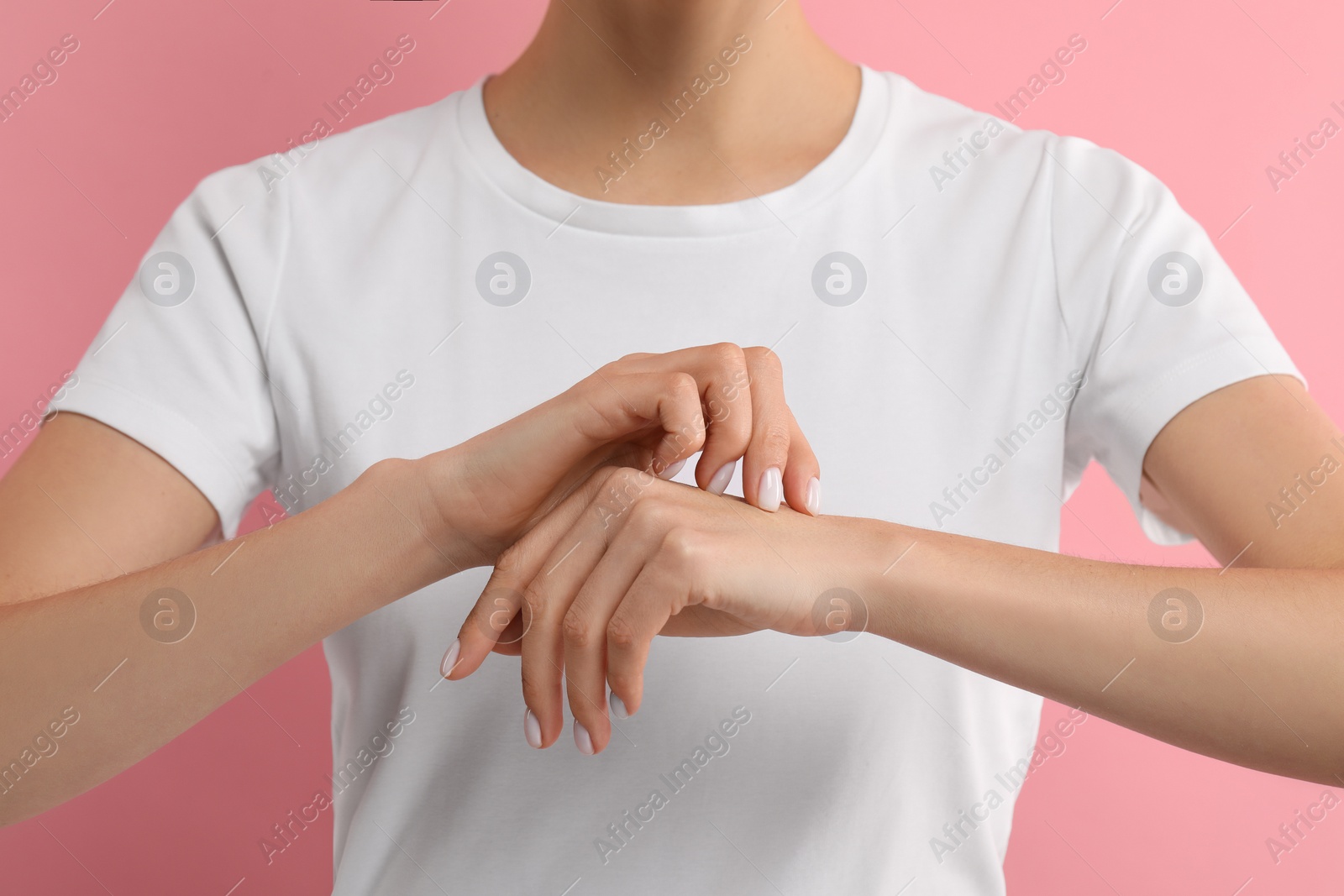 Photo of Woman with dry skin checking her arm on pink background