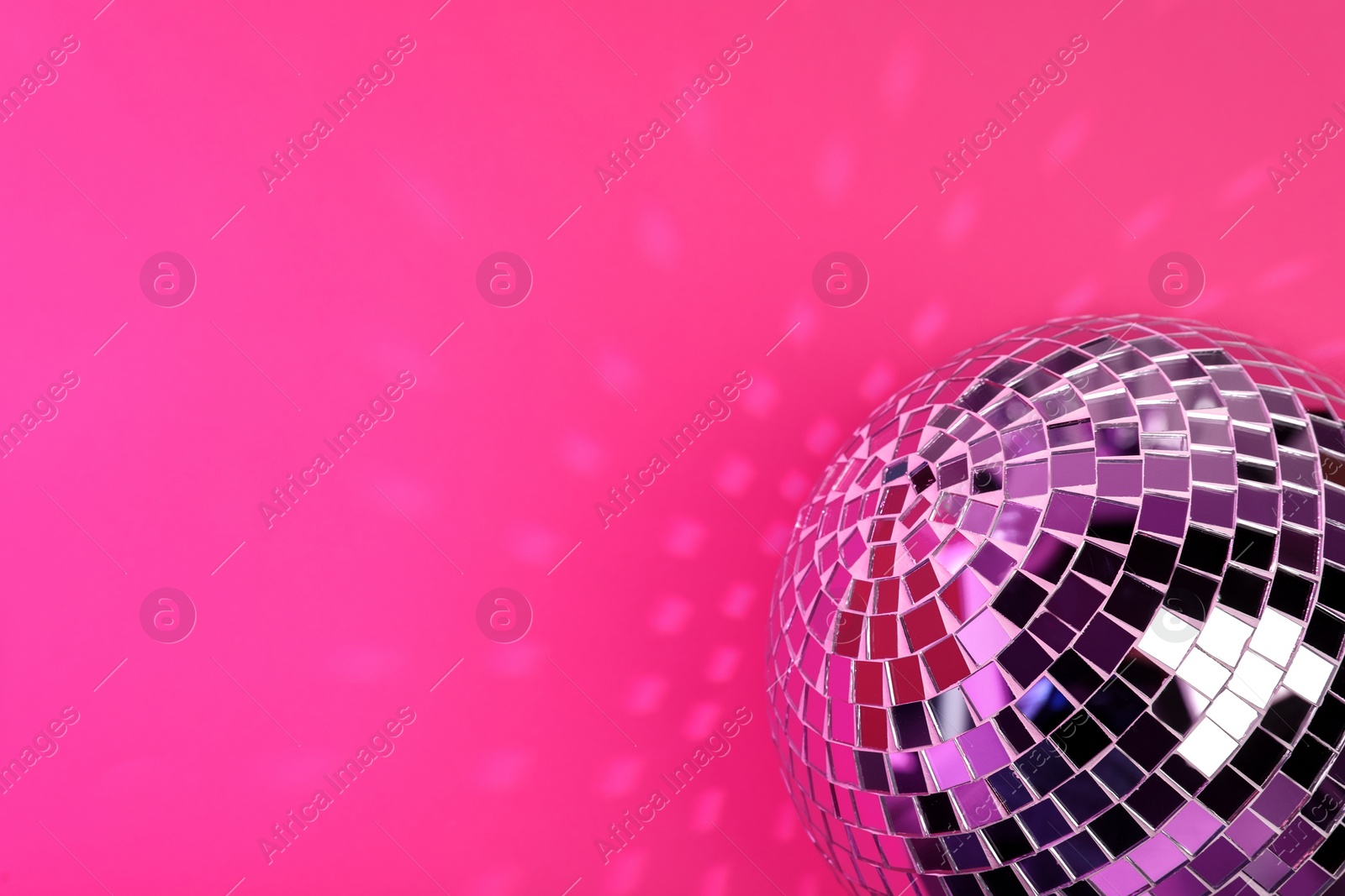 Photo of Shiny disco ball on pink background. Space for text