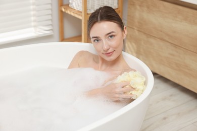 Photo of Woman taking bath with shower gel in bathroom