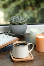 Cup of coffee with books and home decor on wooden window sill