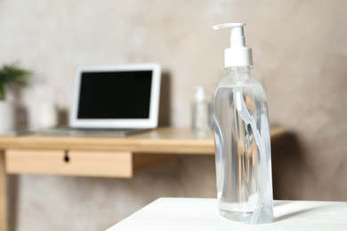 Photo of Dispenser bottle with antiseptic gel on table indoors. Space for text