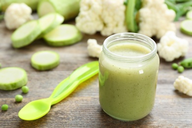 Jar with tasty baby food on table