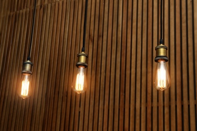 Photo of Pendant lamps with light bulbs on wooden background