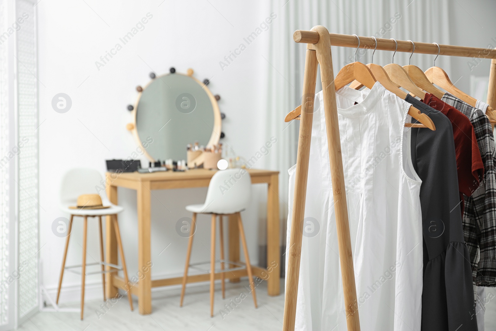 Photo of Hangers with stylish clothes on rack in makeup room. Space for text