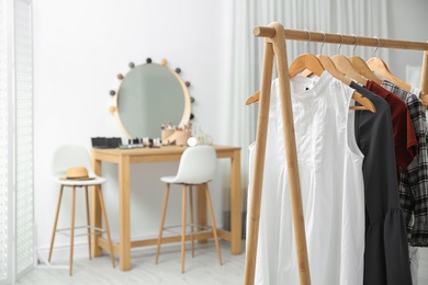 Photo of Hangers with stylish clothes on rack in makeup room. Space for text