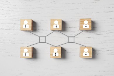 Teamwork. Cubes with human icons linked together symbolizing cooperation on white wooden background, top view