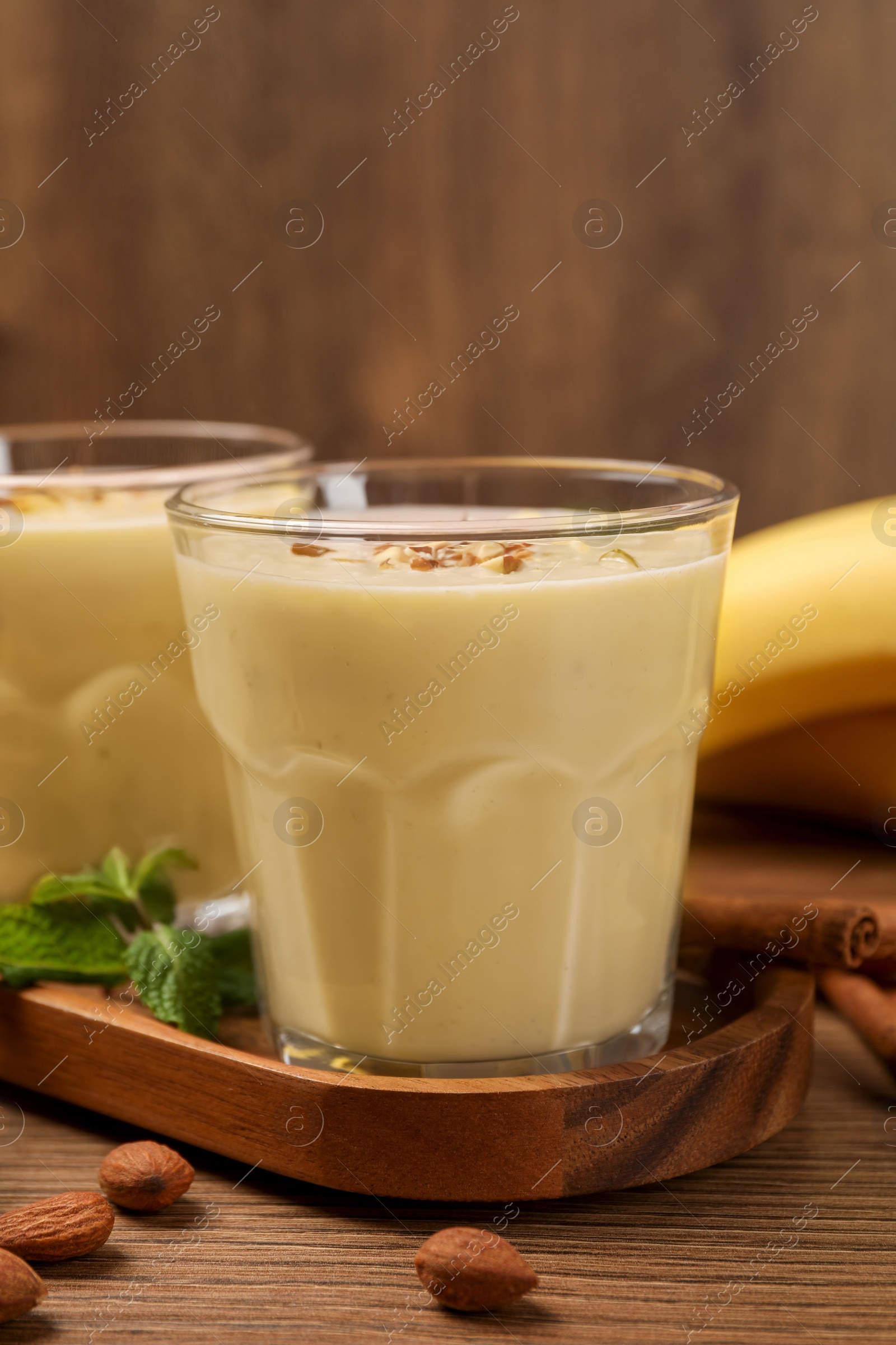 Photo of Tasty banana smoothie with almond and cinnamon on wooden table